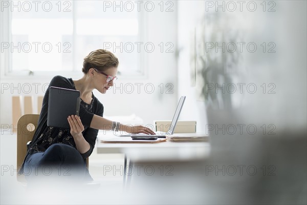 Businesswoman using laptop in office.