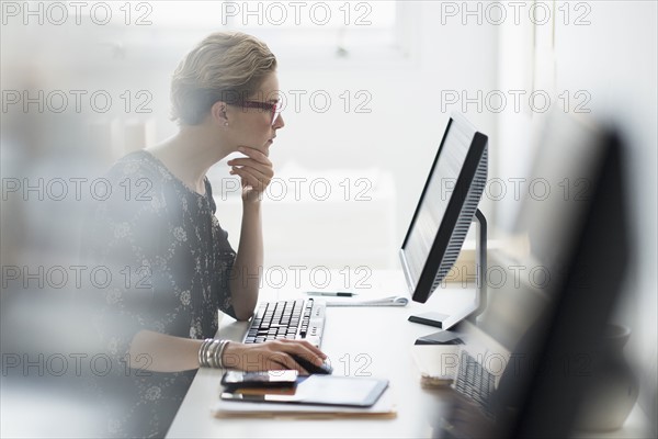 Side view of business woman working on desktop pc in office.