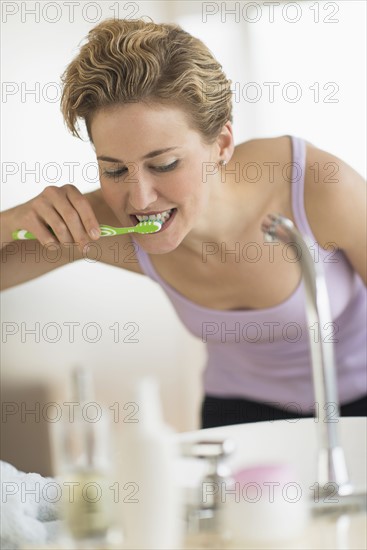 Young woman brushing teeth in bathroom.