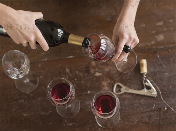 Elevated view of woman pouring red wine.