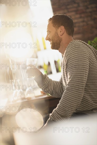 Side view of man having drink in bar.