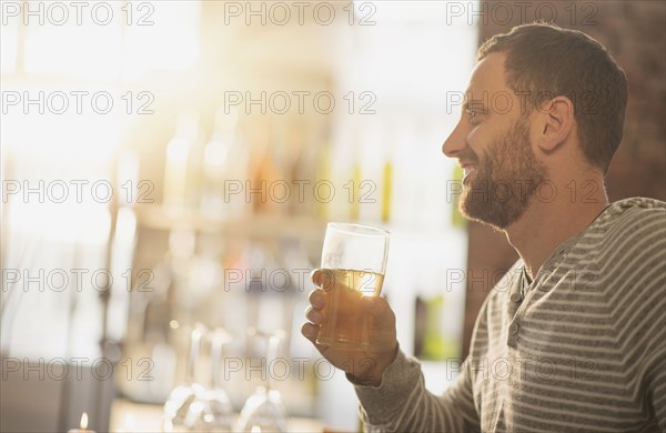 Side view of man having drink in bar.