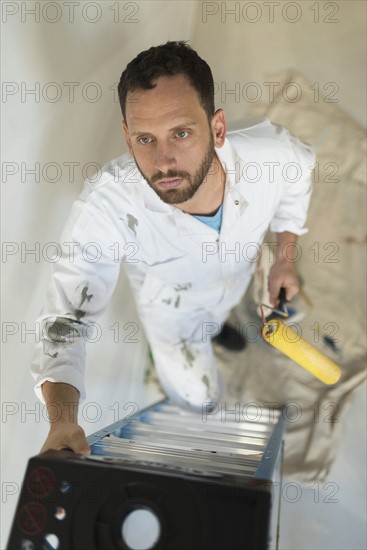 Man climbing ladder with paint roller.