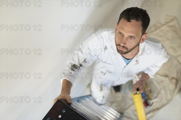 Man climbing ladder with paint roller.