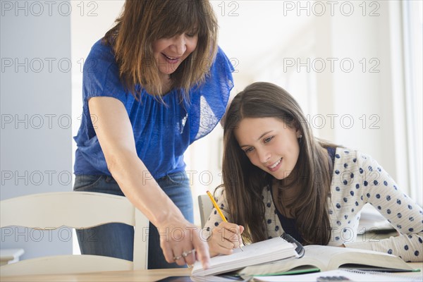 Mother helping daughter (14-15) with homework