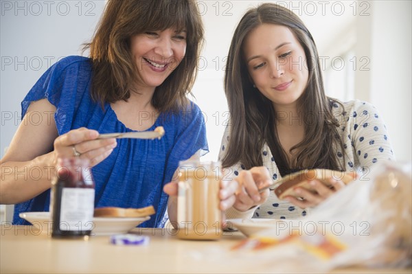 Mother and daughter (14-15) making peanut butter and jelly sandwiches