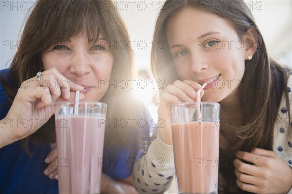 Portrait of mother and daughter (14-15) drinking milkshakes