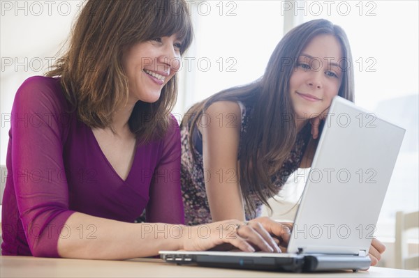 Teenage girl (14-15) using laptop with her mom at home