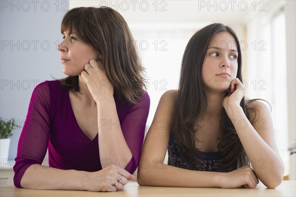 Frustrated teenage girl (14-15) and her mom sitting at table