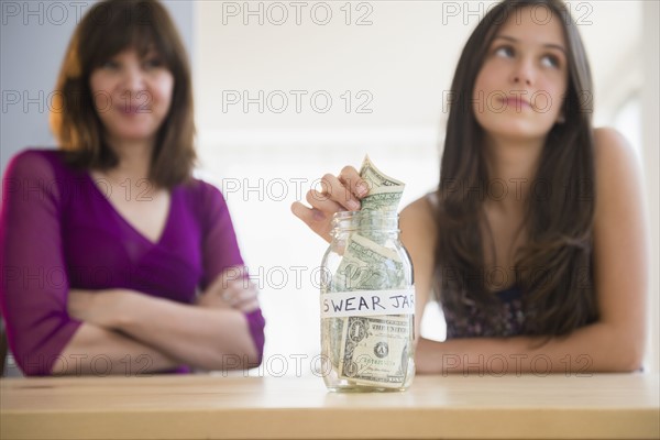 Teenage girl (14-15) putting money in swear jar