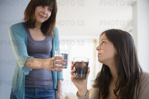 Mom encouraging teenage girl (14-15) to drink mineral water