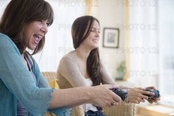 Teenage girl (14-15) playing video games with her mom
