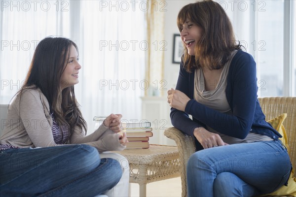 Teenage girl (14-15) talking with her mom in living room