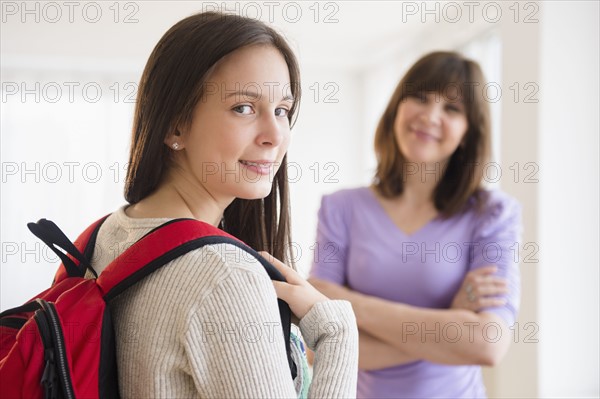 Portrait of teenage student (14-15), mother in background