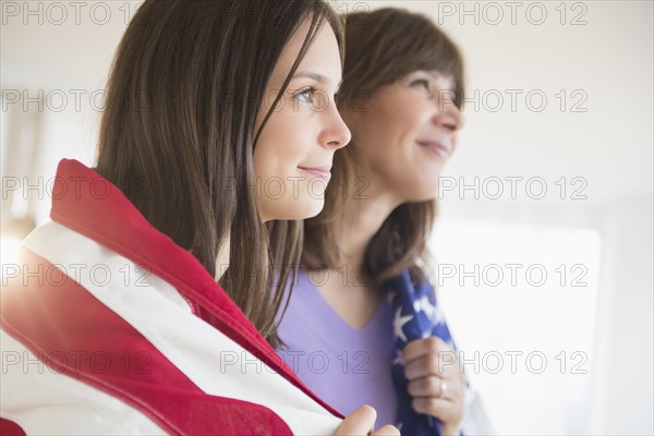 Teenage girl (14-15) and her mom wrapped in American Flag on Fourth of July