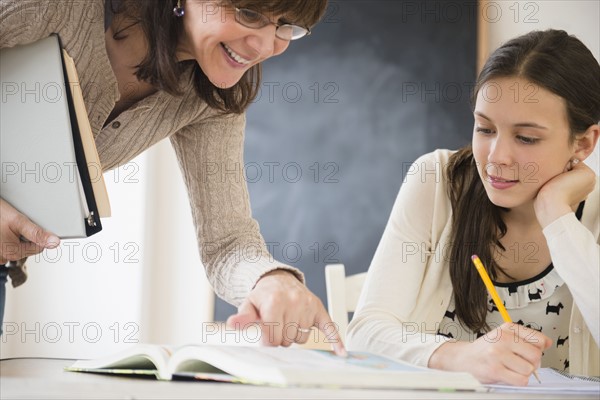 Teacher explaining teenage girl (14-15) how to do homework