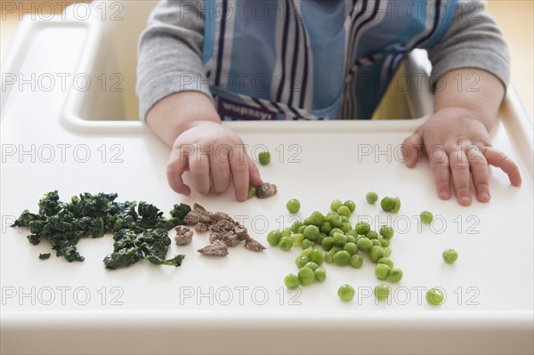 Baby girl (12-17 months) eating steak, spinach and green peas