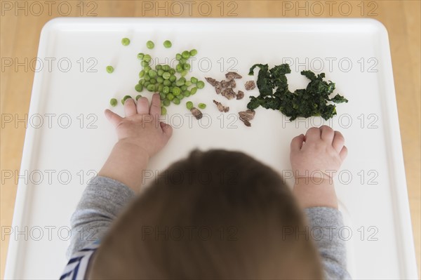 Baby girl (12-17 months) eating steak, spinach and green peas
