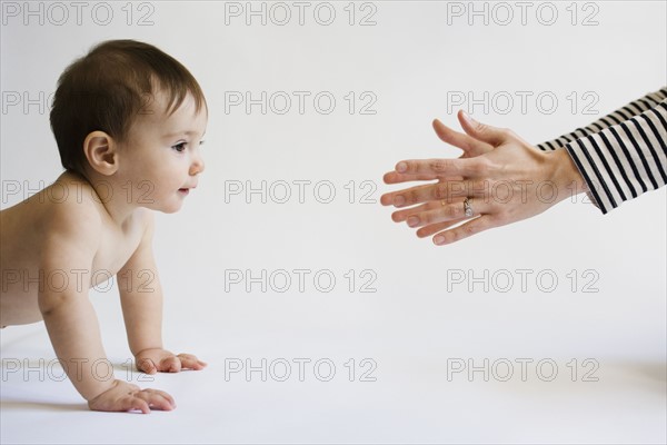 Mother encouraging her daughter (12-17 months) to walk