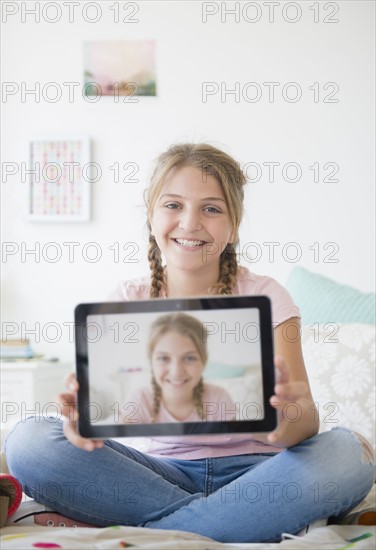 Girl (12-13) holding tablet with selfie