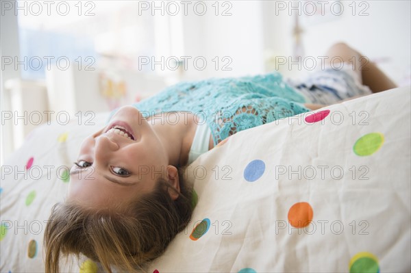 Girl (12-13) lying down on bed smiling