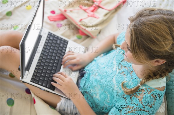 Girl (12-13) using laptop in bedroom