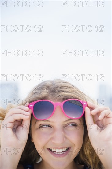 Girl (12-13) with pink sunglasses