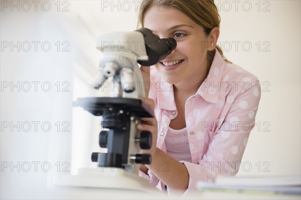 Girl (12-13) using microscope
