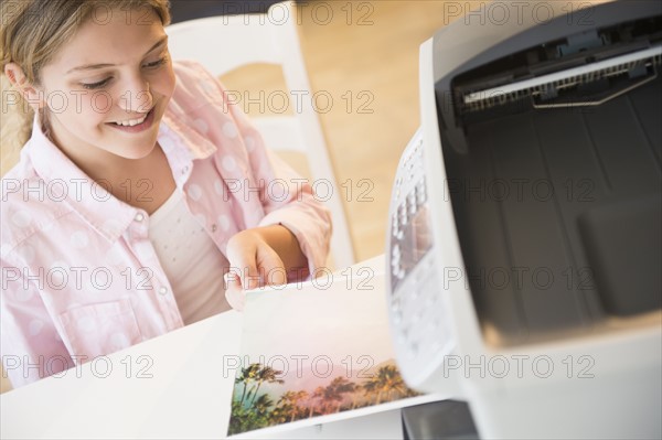 Girl (12-13) waiting for photo next to printer