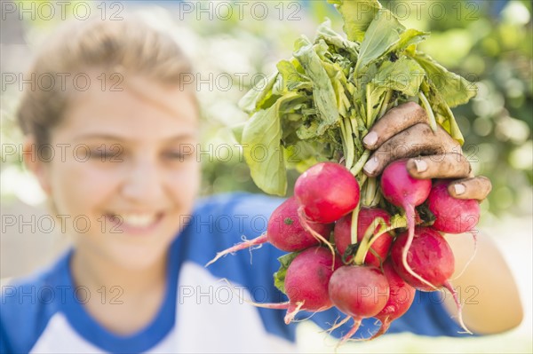 Girl (12-13) showing bunch of radish