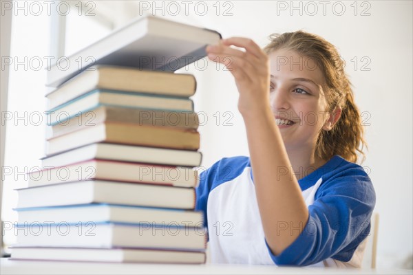 Portrait of teenage girl (12-13) stacking books