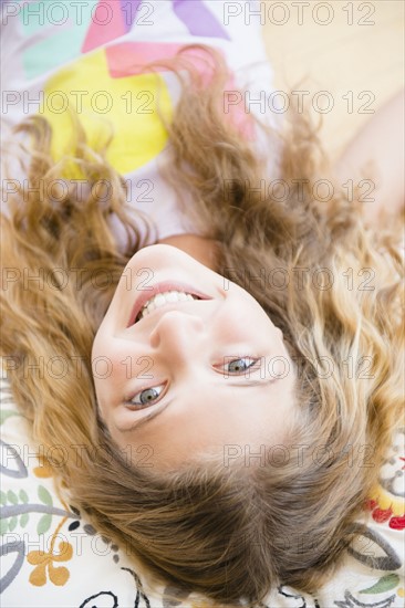 Portrait of smiling teenage girl (12-13) lying on pillow