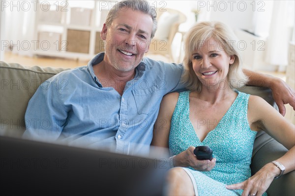Portrait of couple sitting on sofa watching TV