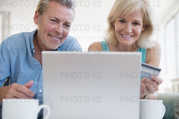 Portrait of couple using laptop, with credit card in view