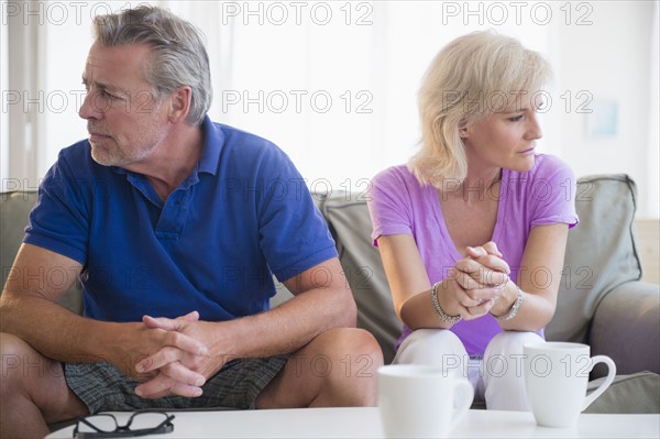 Portrait of couple sitting on sofa, looking away from each other