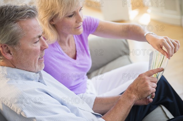Portrait of couple sitting on sofa looking at sheet of paper