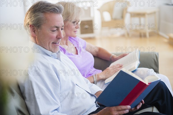 Portrait of couple sitting on sofa reading books