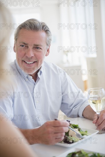 Portrait of man eating and drinking white wine at restaurant