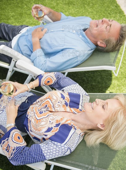 Portrait of couple relaxing on sun loungers on lawn