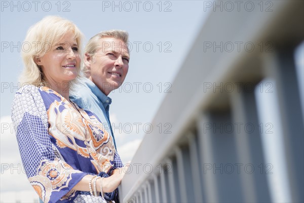 Portrait of couple leaning at railing, looking at view