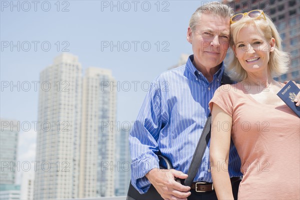 Portrait of couple with passport against skyscrapers