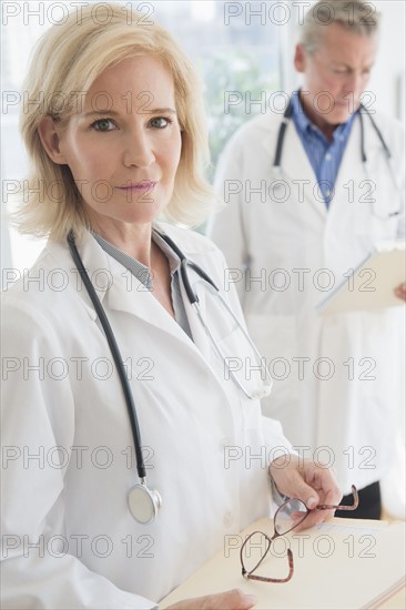 Portrait of female doctor holding clipboard and eyeglasses