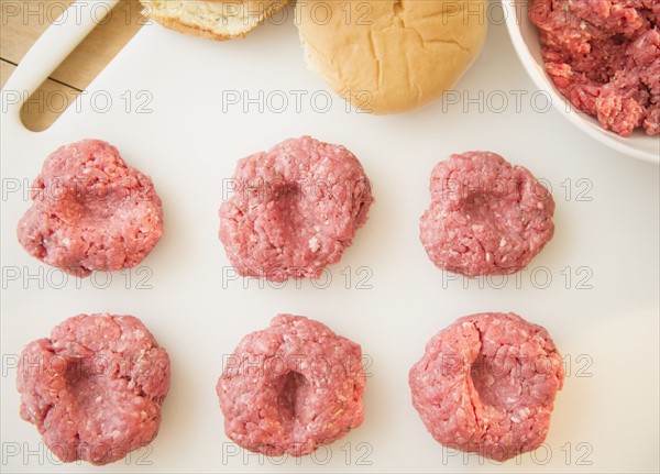 Close-up shot of meatballs in row on white cutting board