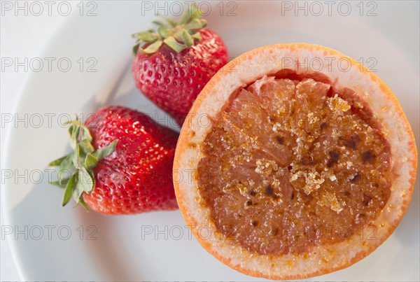 Studio shot of grapefruit with caramelized sugar and strawberries