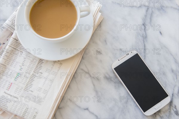 Studio shot of coffee cup, newspaper and smart phone