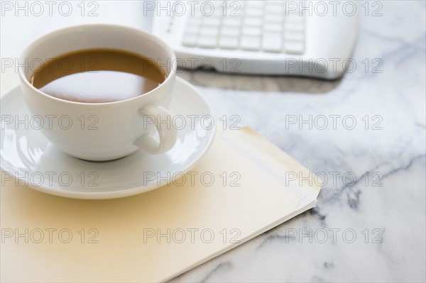 Studio shot of coffee cup, computer keyboard and files