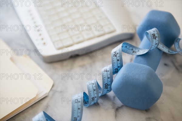 Studio shot of weight, measuring tape, files and computer keyboard