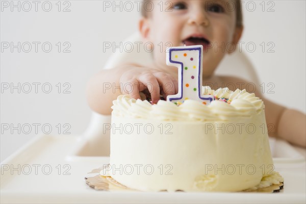 Studio shot of baby (12-17 months) reaching for cake
