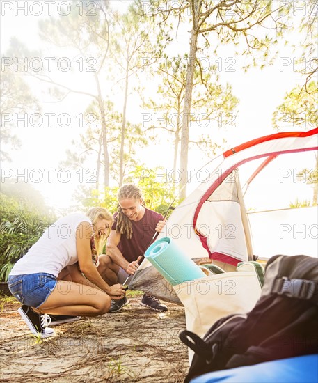 Couple setting up tent in forest