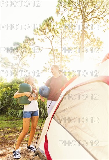 Couple standing next to tent in forest